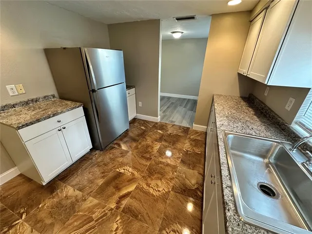 a kitchen with granite countertop a refrigerator and a sink