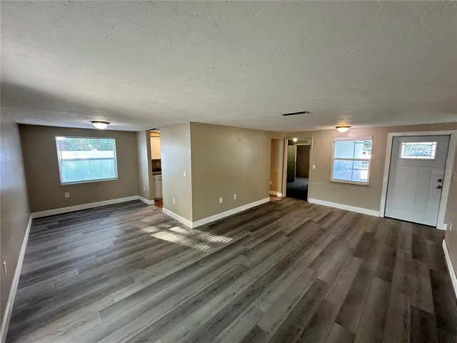 a view of an empty room and window and wooden floor