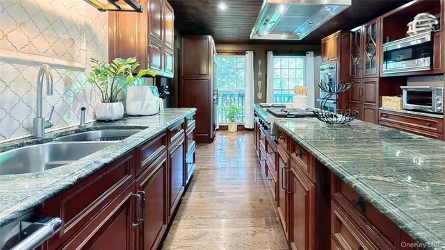 a view of kitchen island with granite countertop sink and wooden floor