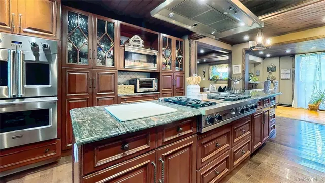 a kitchen with stainless steel appliances kitchen island granite countertop a table chairs and a wooden floors