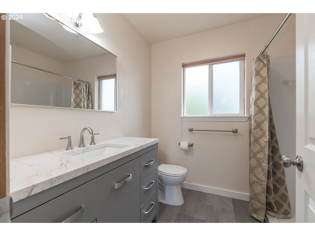 7822 Southwest 171st Place Beaverton, OR 97007 - Photo 19 of 20 a bathroom with a granite countertop toilet a sink a mirror and a window