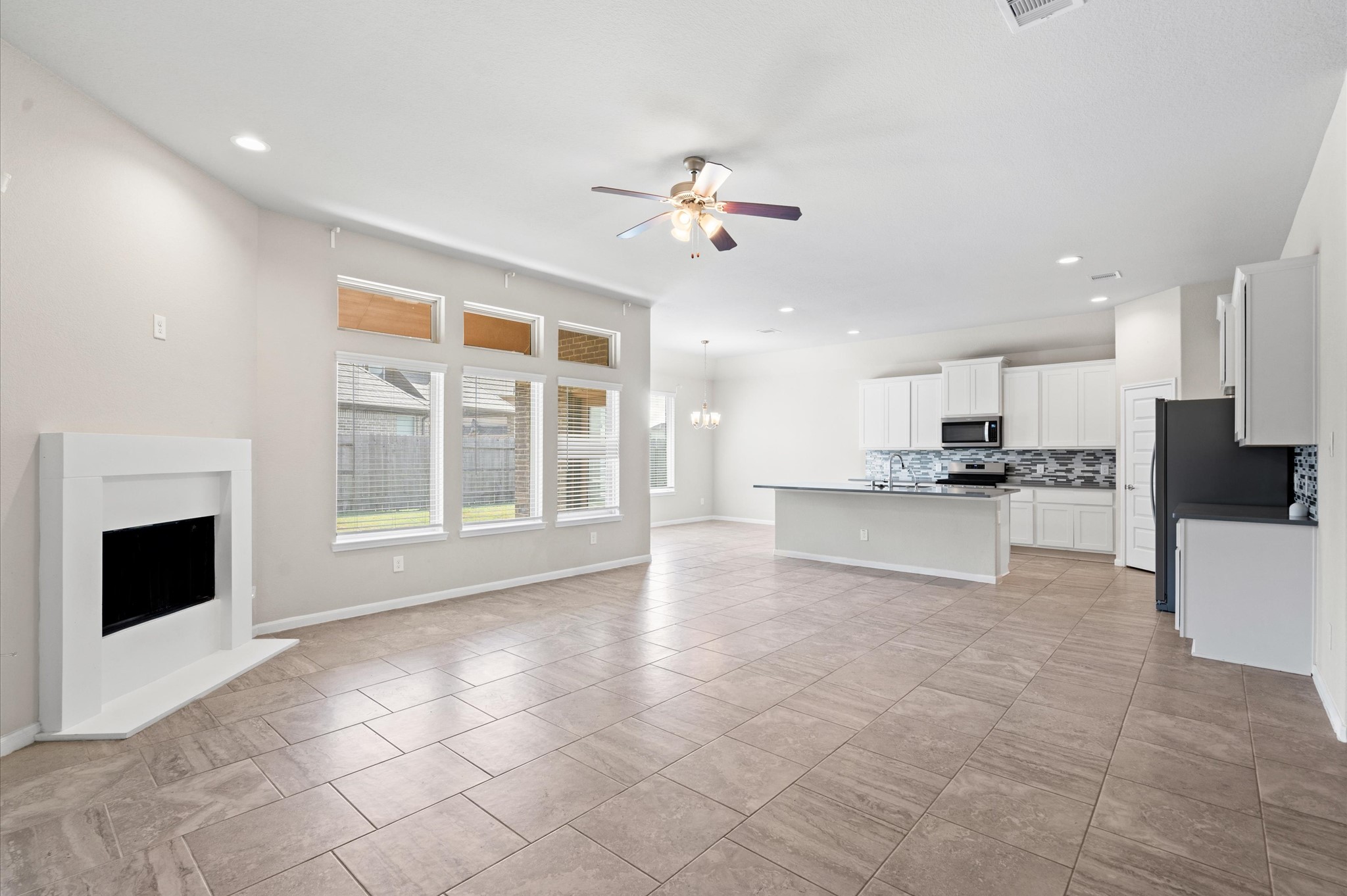 410 Richfish Run Drive Rosenberg, TX 77469 - Photo 6 of 30 Bright and airy great room featuring a cozy fireplace, a ceiling fan for comfort, and ample natural light, perfect for relaxation or entertaining.
