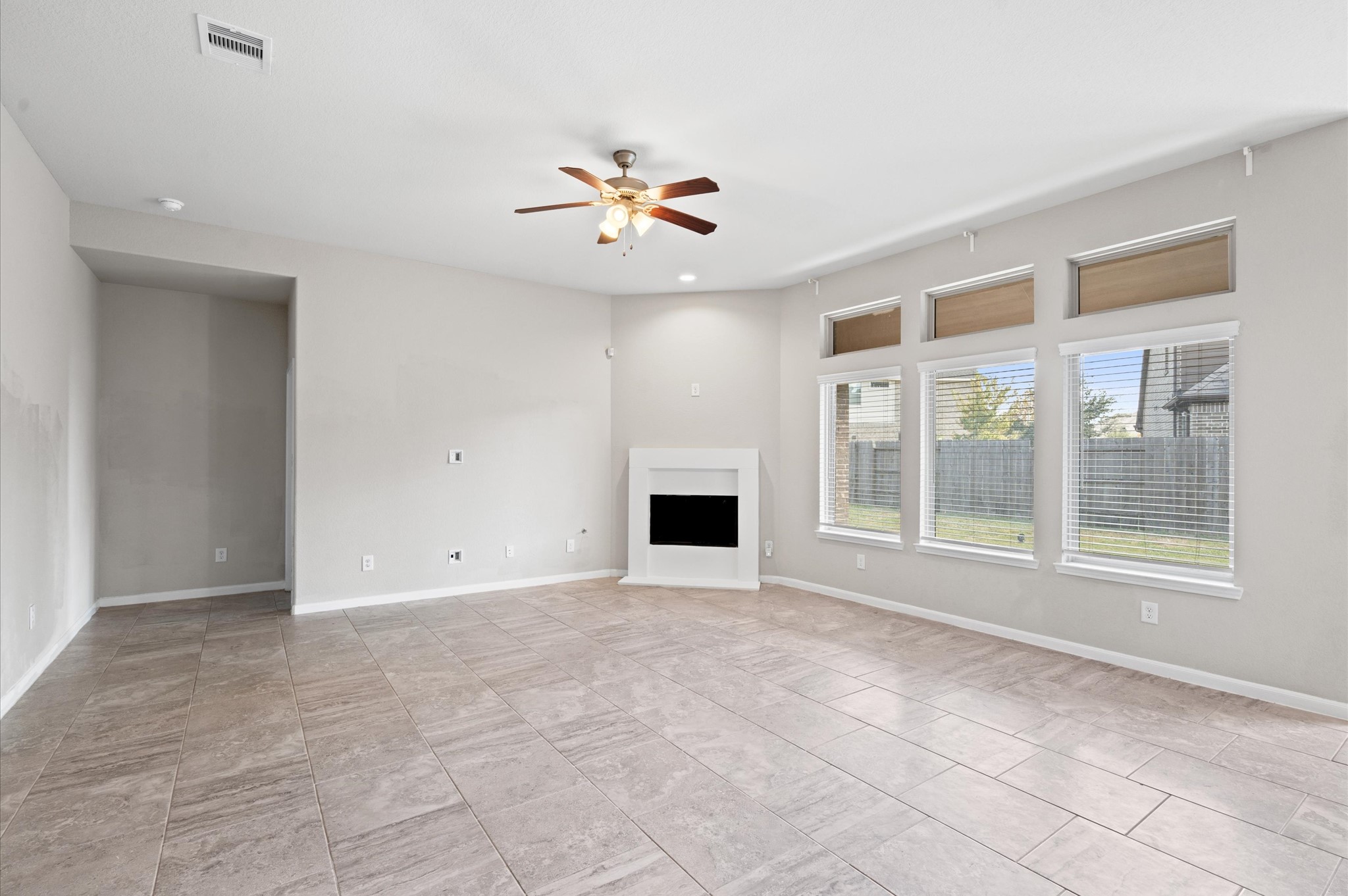 410 Richfish Run Drive Rosenberg, TX 77469 - Photo 7 of 30 Spacious living area bathed in sunlight, featuring an elegant fireplace and a stylish ceiling fan.