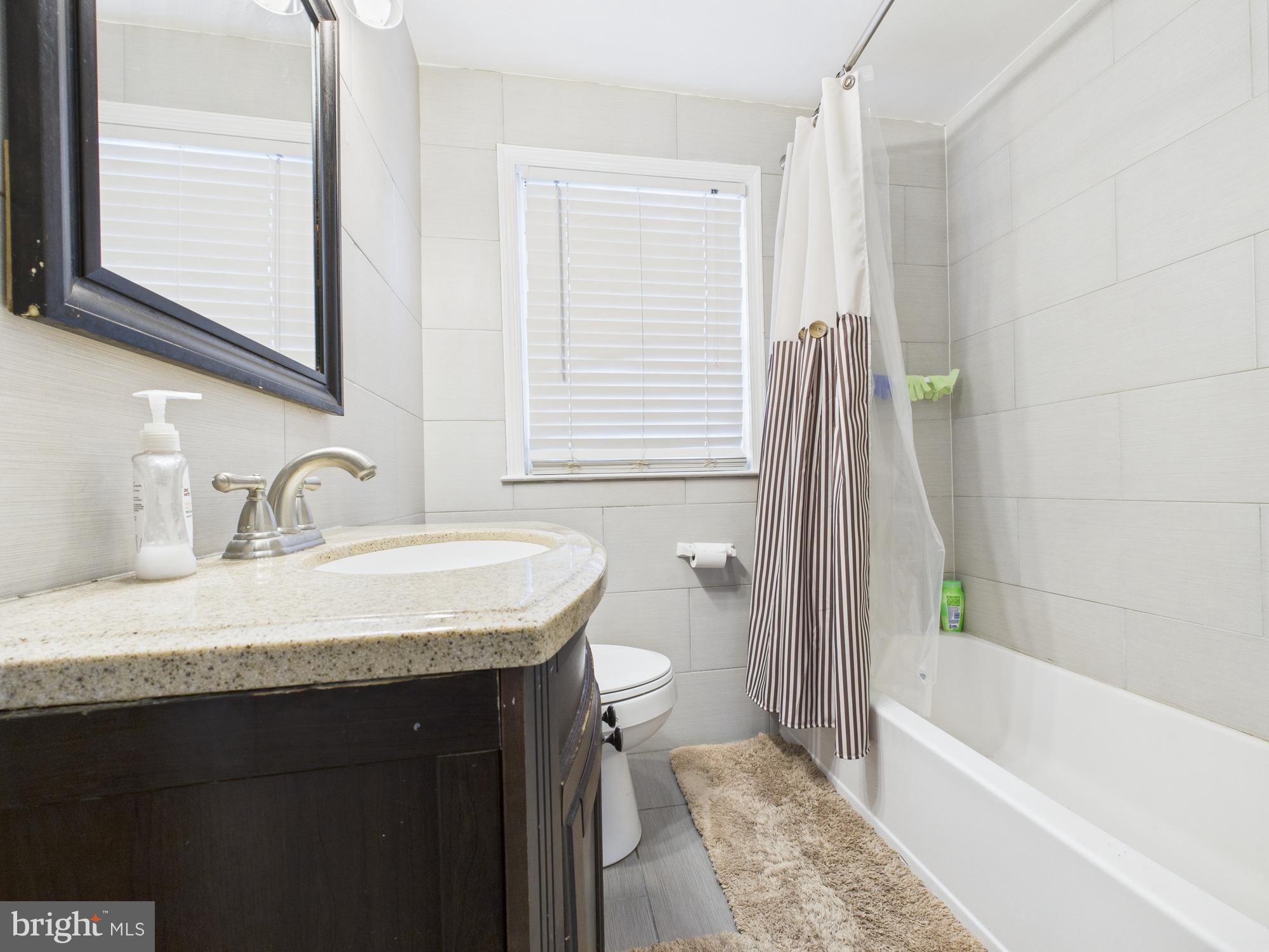 1551 Langford Road Baltimore, MD 21207 - Photo 49 of 52 a bathroom with a granite countertop sink a toilet and bathtub