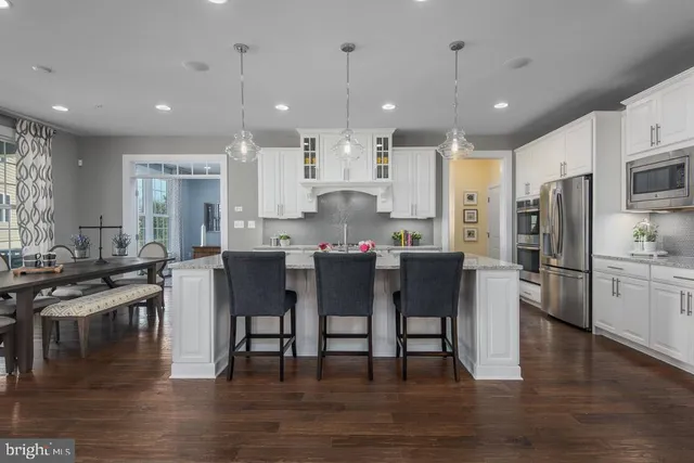 a view of a dining room and livingroom with furniture wooden floor kitchen view and windows
