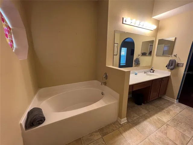 a bathroom with a tub sink and mirror