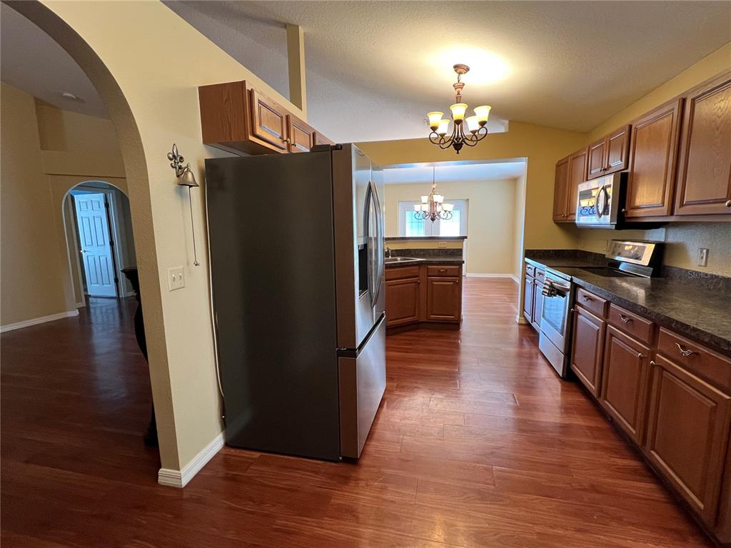 14367 Finsbury Drive Spring Hill, FL 34609 - Photo 5 of 35 a kitchen with stainless steel appliances granite countertop a refrigerator a stove top oven and wooden floors