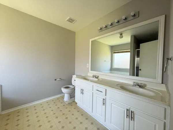 a bathroom with a granite countertop sink a toilet and a mirror