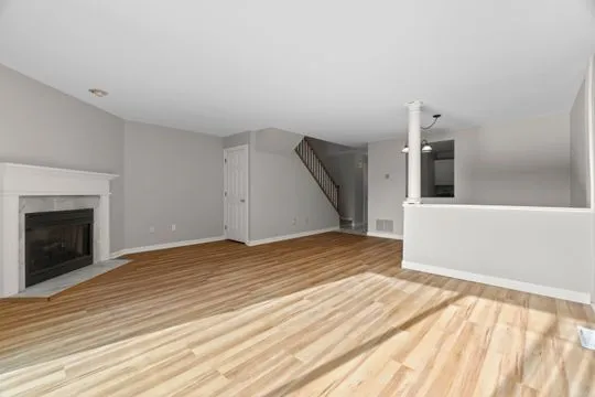 a view of empty room with wooden floor and fireplace