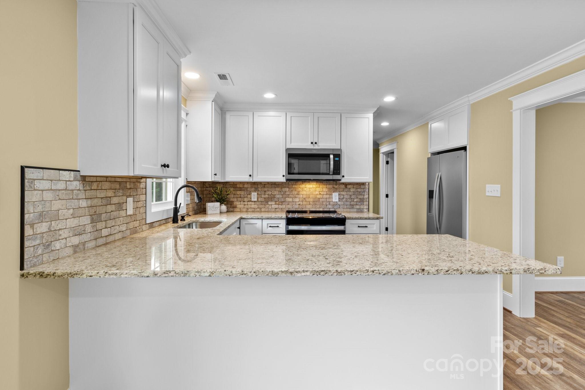 893 Chief Thomas Road Harmony, NC 28634 - Photo 9 of 38 a kitchen with stainless steel appliances granite countertop a sink refrigerator and cabinets