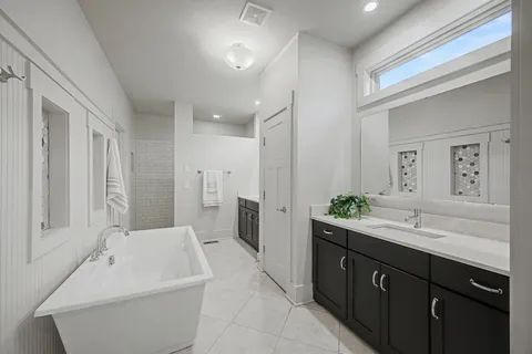 a spacious bathroom with a double vanity sink a large mirror and a bathtub