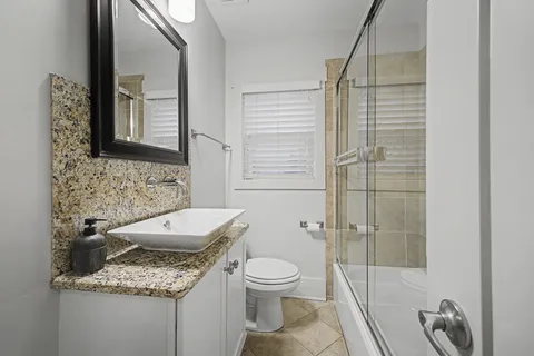 a bathroom with a granite countertop sink toilet and shower