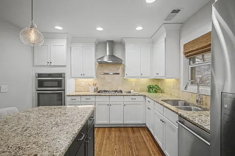 a kitchen with kitchen island granite countertop a sink a counter space appliances and cabinets