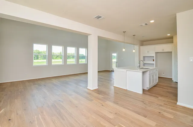 a view of an empty room with wooden floor and a ceiling fan