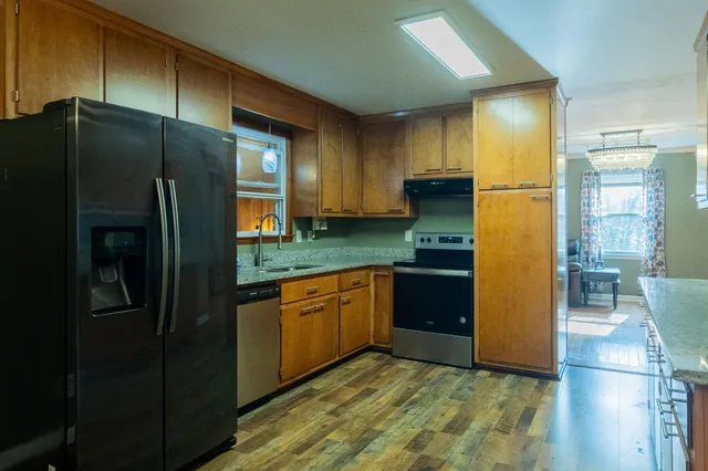 a kitchen with stainless steel appliances granite countertop a refrigerator and a wooden cabinets