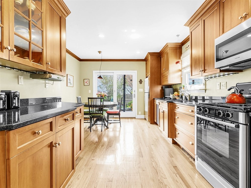 4 Brier Road Boston, MA 02132 - Photo 17 of 34 a kitchen with stainless steel appliances granite countertop a stove top oven a sink a dining table and chairs with wooden floor