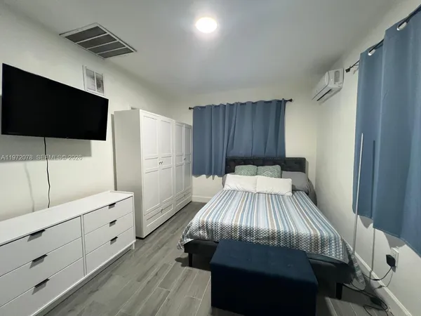 a spacious bedroom with a bed and a flat screen tv