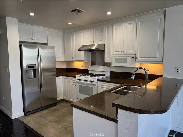 a kitchen with stainless steel appliances granite countertop a sink a stove a refrigerator and a refrigerator