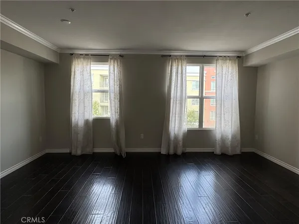 an empty room with wooden floor and windows with curtains view