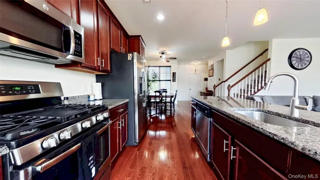 a kitchen with stainless steel appliances granite countertop a stove a sink dishwasher and a microwave with wooden floor