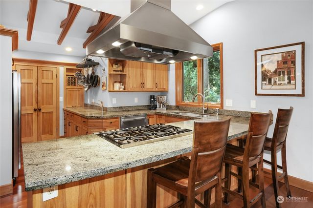 a kitchen with stainless steel appliances granite countertop a stove a sink dishwasher and cabinets with wooden floor