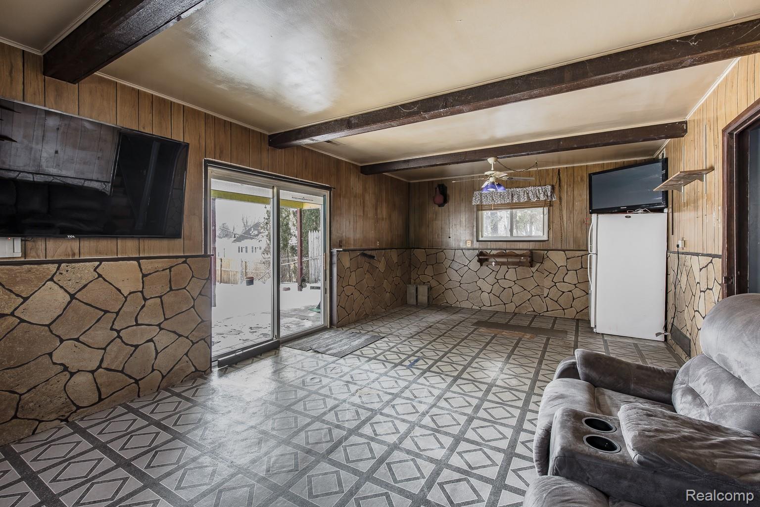 8670 North Eston Road Clarkston, MI 48348 - Photo 19 of 29 Unfurnished living room featuring wooden walls, beamed ceiling, and tile patterned floors