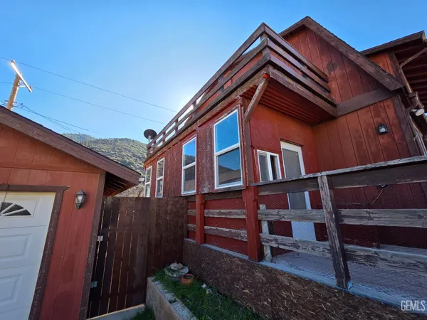 a backyard of a house with wooden fence and a bench
