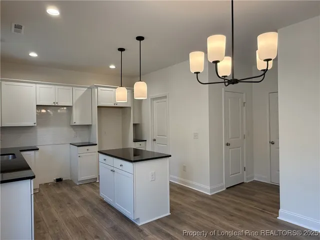 a kitchen with stainless steel appliances granite countertop a sink a stove and a wooden floors