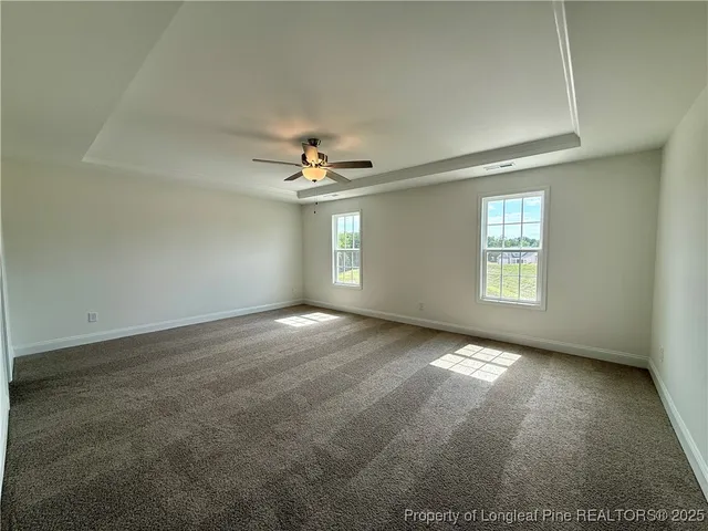 an empty room with windows and chandelier fan