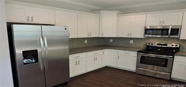 a kitchen with granite countertop white cabinets and stainless steel appliances