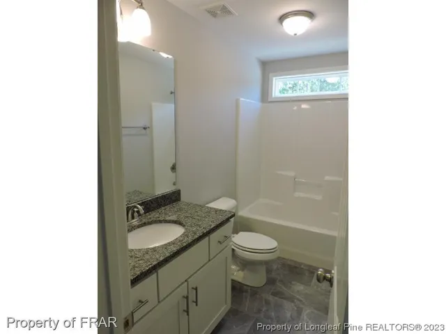 a bathroom with a granite countertop toilet a sink and a mirror