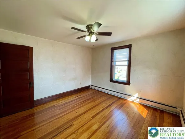 a view of an empty room with window and wooden floor