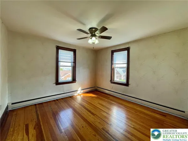 a view of an empty room with window and wooden floor