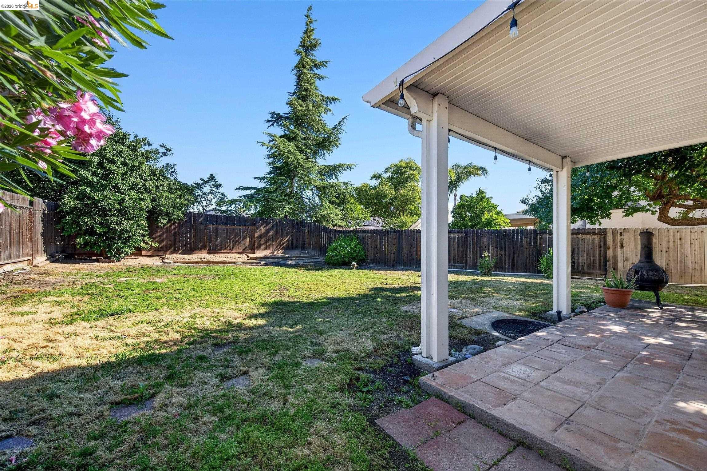 1120 Deerpark Road Oakley, CA 94561 - Photo 29 of 30 Expansive backyard featuring a covered patio with string lighting, a built-in fire pit, and privacy fencing