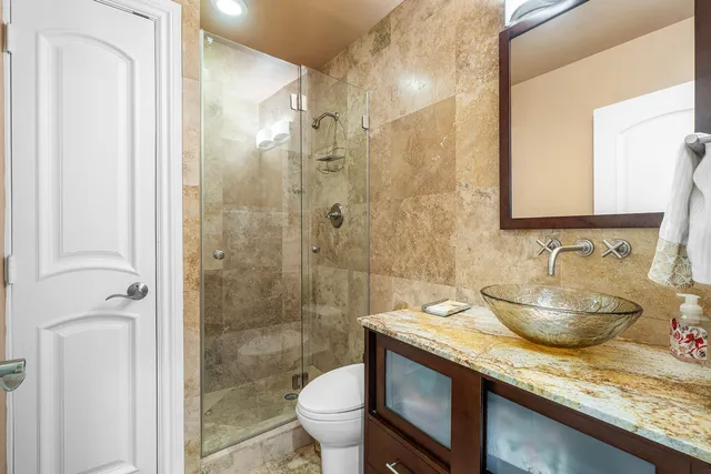 a bathroom with a granite countertop sink a toilet and shower