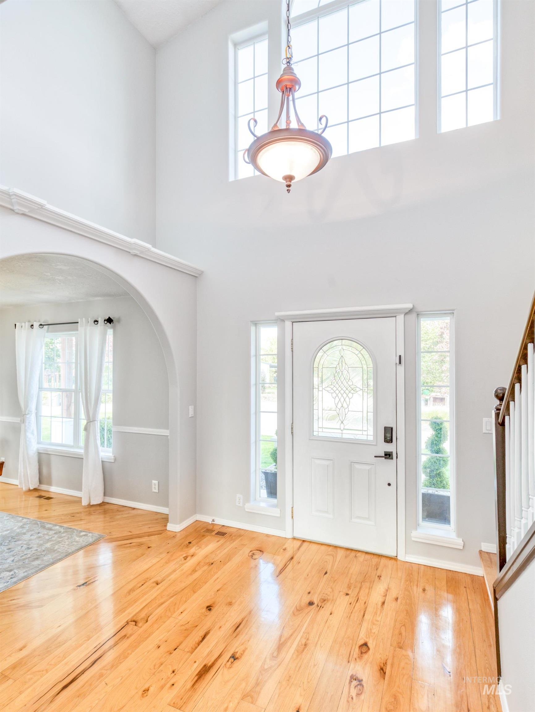 16277 Sand Hollow Road Caldwell, ID 83607 - Photo 11 of 39 Foyer featuring arched walkways, a towering ceiling, light wood-style flooring, and stairs