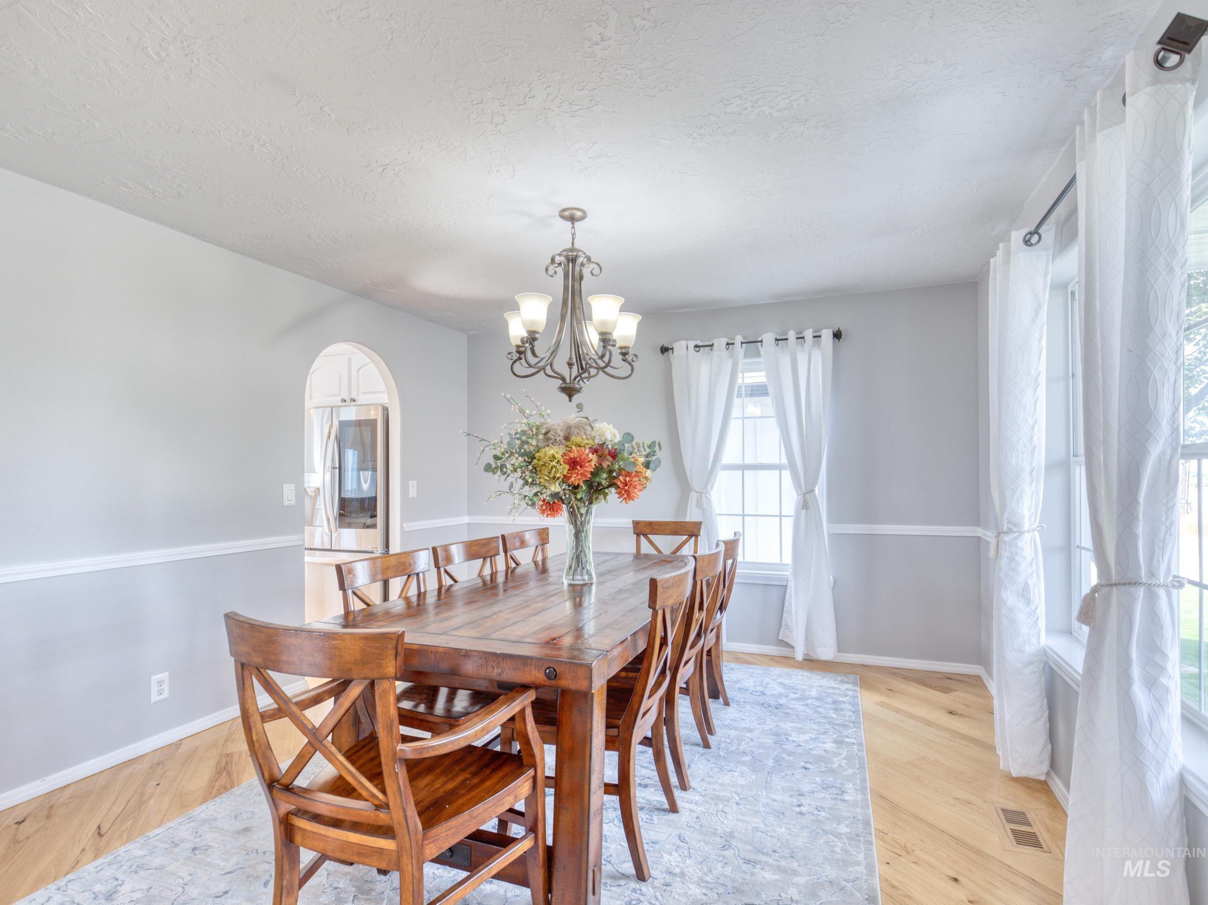 16277 Sand Hollow Road Caldwell, ID 83607 - Photo 12 of 39 Dining room featuring light wood-type flooring, arched walkways, a chandelier, and a textured ceiling
