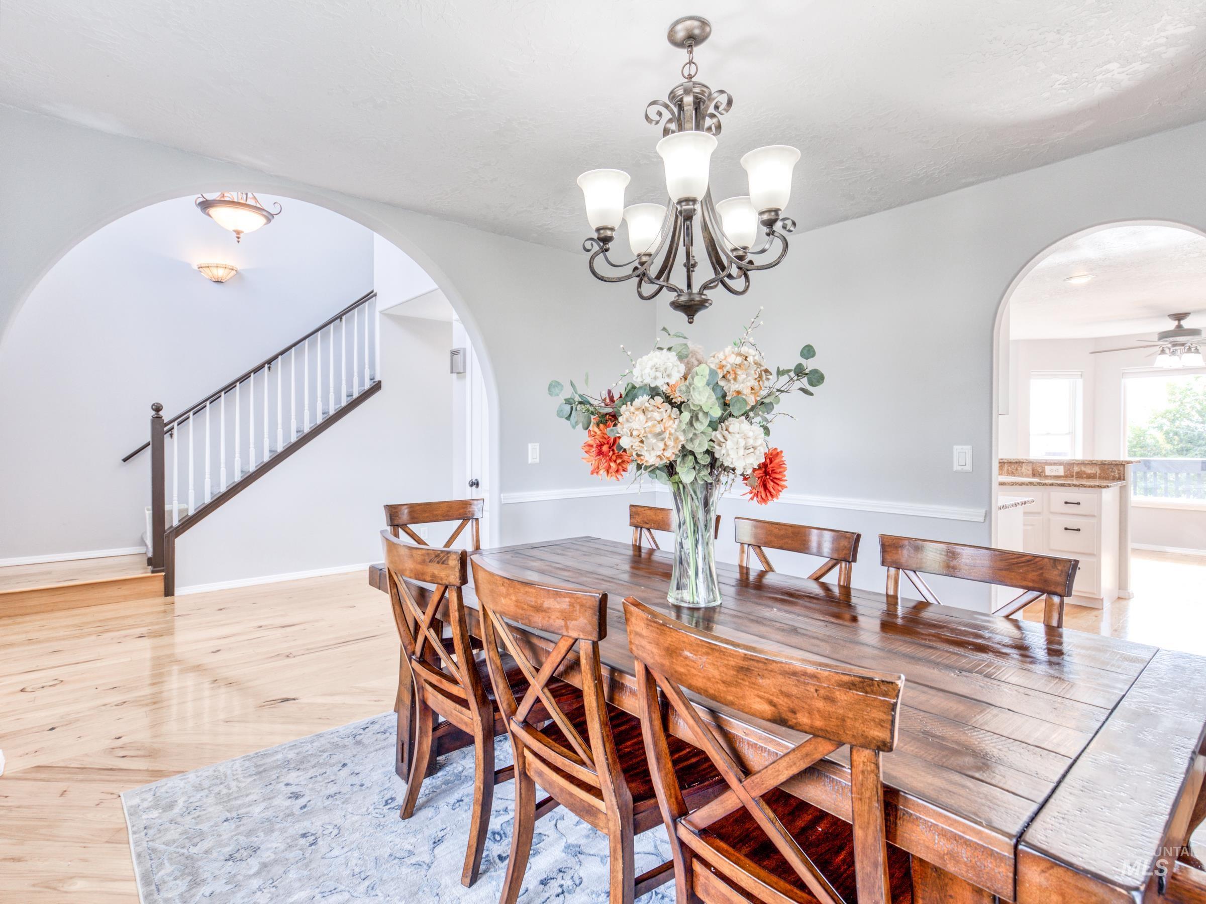 16277 Sand Hollow Road Caldwell, ID 83607 - Photo 13 of 39 Dining room featuring arched walkways, stairs, light wood-style floors, and a chandelier