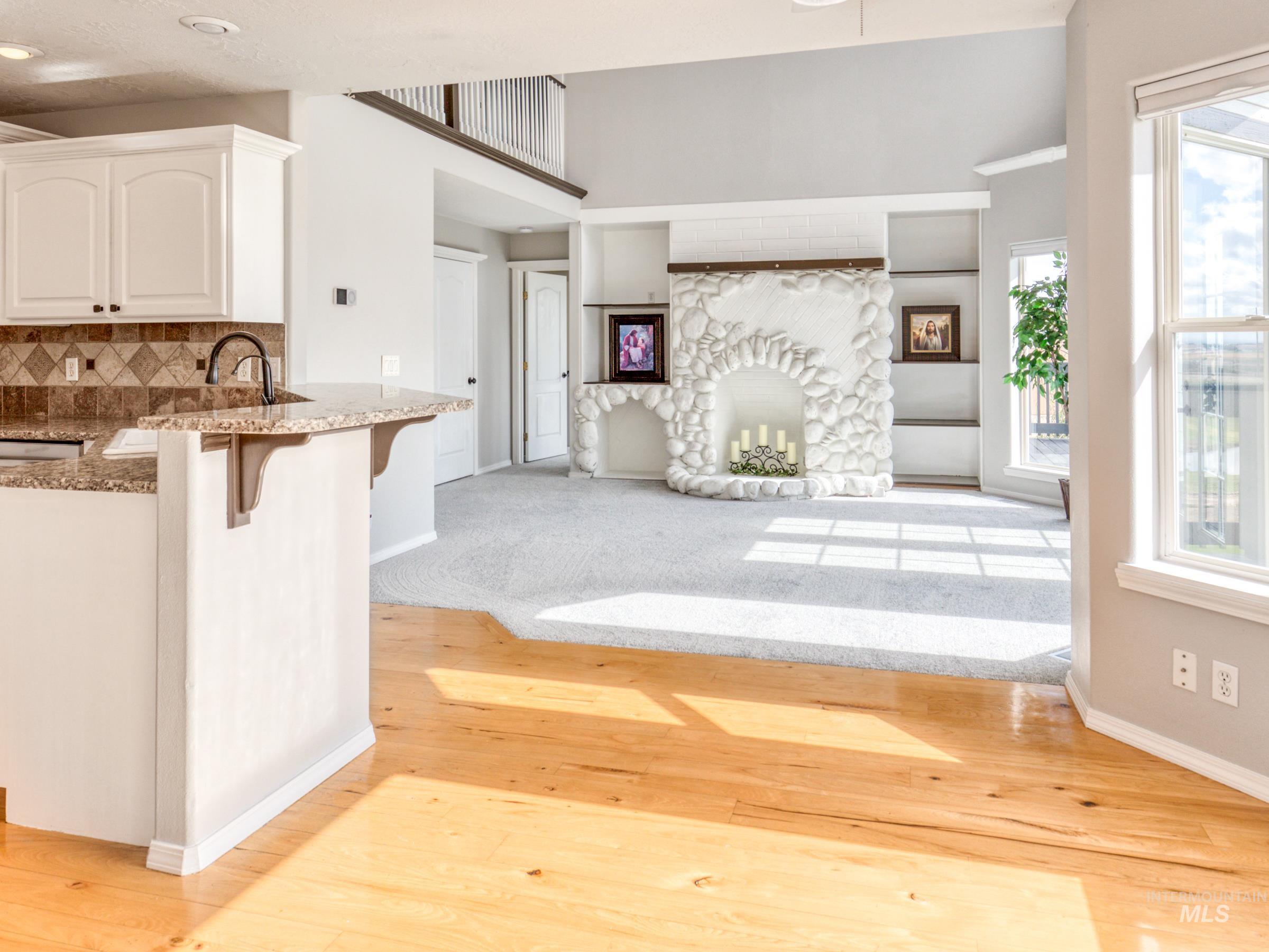 16277 Sand Hollow Road Caldwell, ID 83607 - Photo 39 of 39 Kitchen featuring a breakfast bar area, light wood-style flooring, open floor plan, white cabinetry, and a fireplace