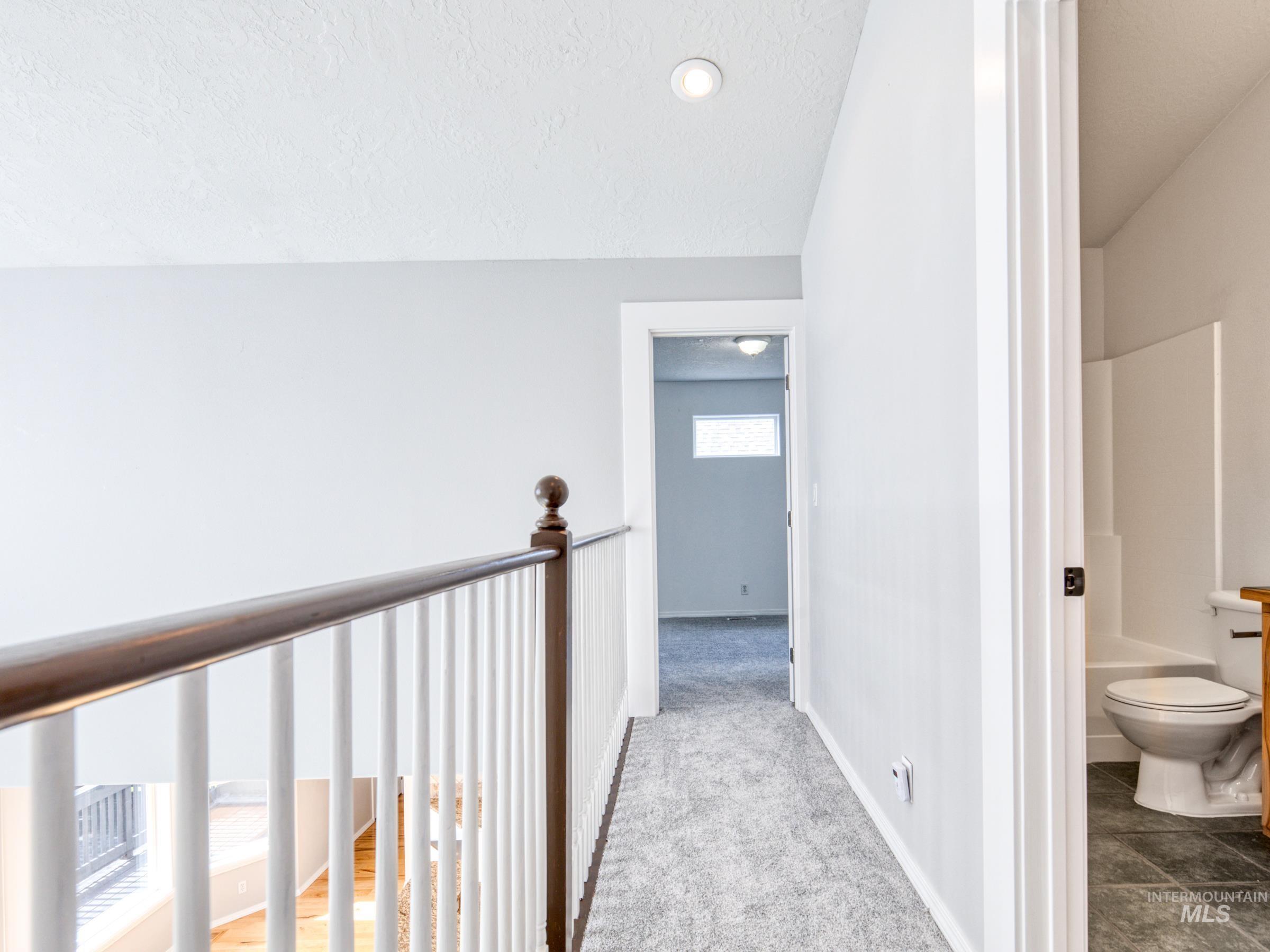 16277 Sand Hollow Road Caldwell, ID 83607 - Photo 24 of 39 Hallway featuring carpet, a textured ceiling, lofted ceiling, and an upstairs landing