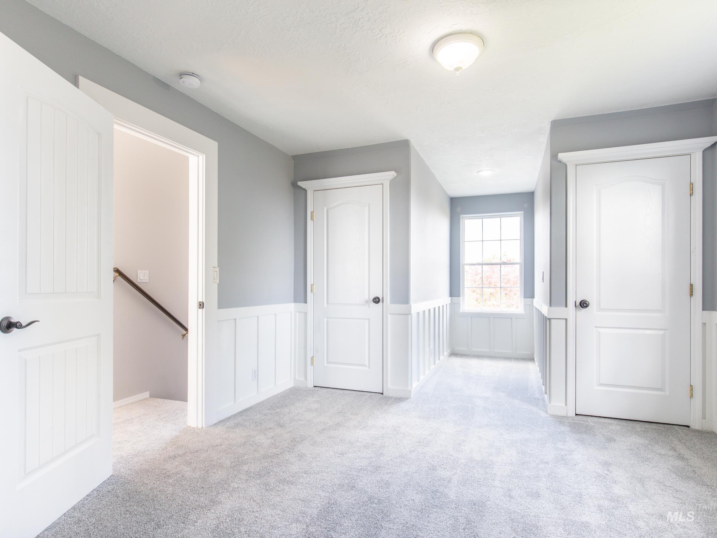 16277 Sand Hollow Road Caldwell, ID 83607 - Photo 27 of 39 Unfurnished bedroom featuring light colored carpet, a wainscoted wall, and a decorative wall