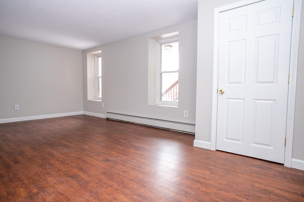35 Cedar Street, Unit 2 Gardner, MA 01440 - Photo 14 of 32 an empty room with wooden floor and windows