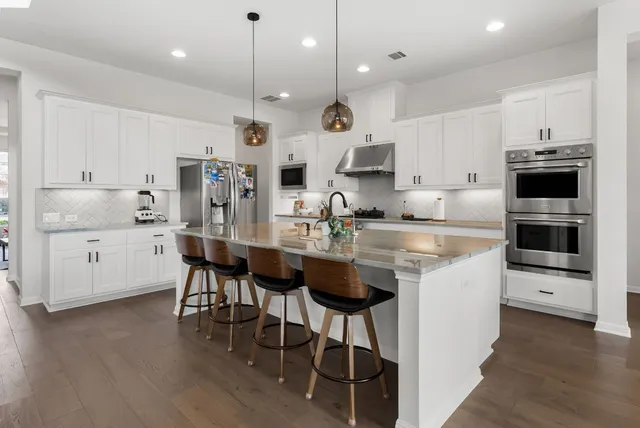 a kitchen with kitchen island granite countertop a sink a counter space stainless steel appliances and cabinets