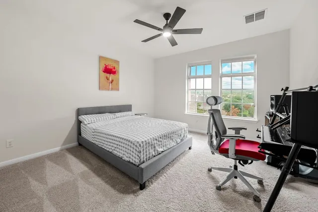 a bedroom with a bed a computer on the desk and a chandelier