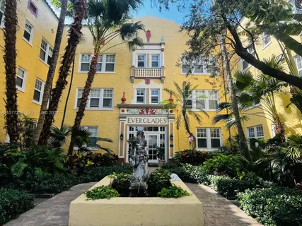 a front view of a multi story residential apartment building with yard and parking
