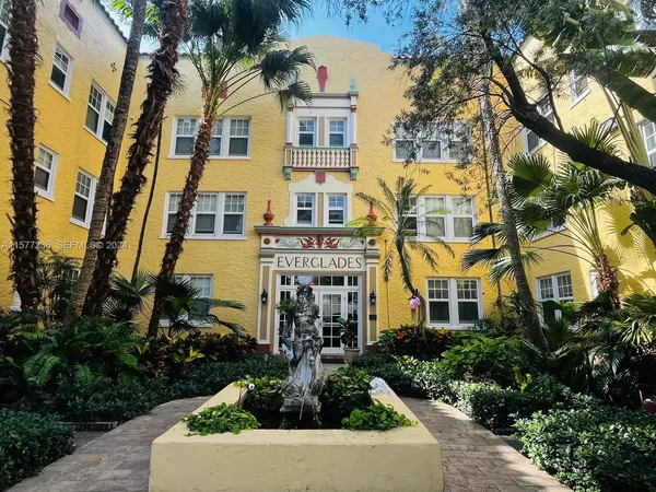 a front view of a multi story residential apartment building with yard and parking