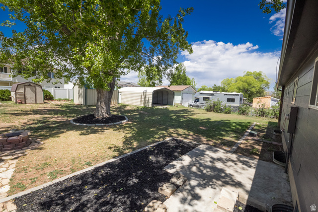 634 South 2100th Street West Vernal, UT 84078 - Photo 51 of 71 Expansive backyard featuring a mature central tree, a brick fire pit, and a concrete patio area