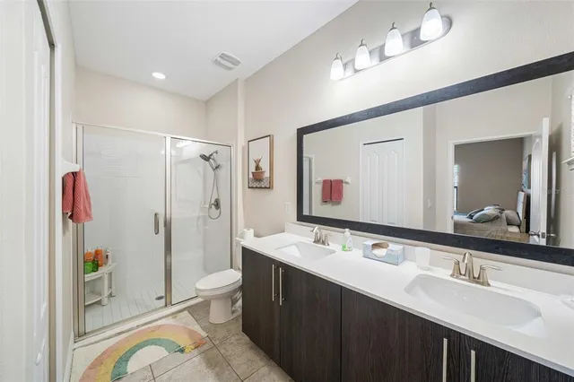 a spacious bathroom with a double vanity sink toilet mirror and shower