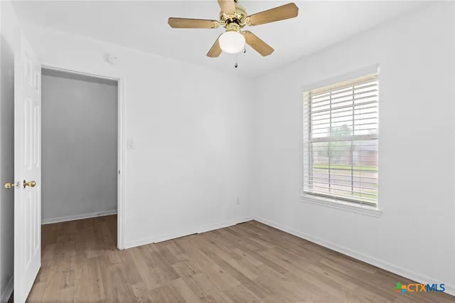 a view of an empty room with wooden floor and a window