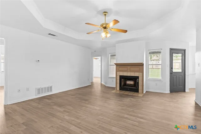 a view of a livingroom with a fireplace a ceiling fan a fireplace and windows